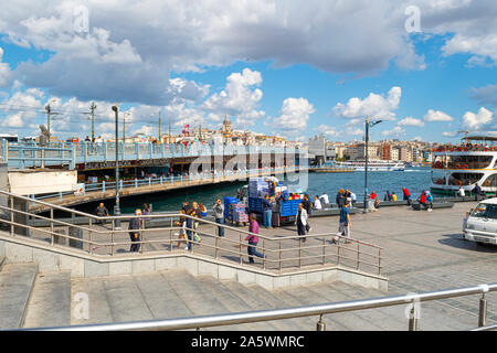 Turisti e Turchi locali vicino al porto presso il Ponte di Galata sul Bosforo, con la Torre di Galata in vista. Foto Stock