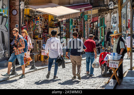 Un Turk vende acqua imbottigliata sul marciapiede vicino a negozi di souvenir e colorati negozi di articoli da regalo in zona collinare in quartiere di Galata di Istanbul in Turchia Foto Stock