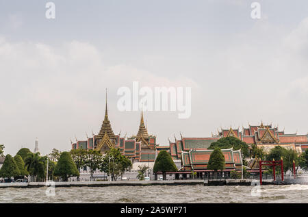 Città di Bangkok, Tailandia - 17 Marzo 2019: il fiume Chao Phraya. National Grand Palace sotto luce blu cloudscape e fogliame verde nella parte anteriore. Guglie e s Foto Stock