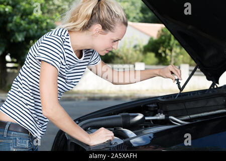 Ragazza controlla l'olio nel motore di automobili Foto Stock