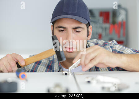 Uomo che lavora con un martello nelle sue mani Foto Stock