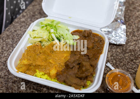 Da asporto - Curry Curry di pollo e curry di rampa di colore giallo con riso in bianco di un contenitore in plastica Foto Stock