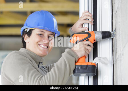 Ragazza sorridente la realizzazione di fori in una parete Foto Stock