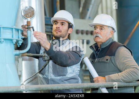 Lavoratori la calibrazione di una macchina industriale Foto Stock