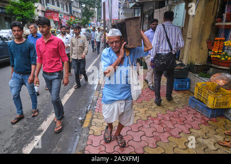 Tradizionalmente un vestito Maharashtrian uomo in area business Kalbadevi Road, Bhuleshwar, Mumbai, India, portando una scatola di legno Foto Stock