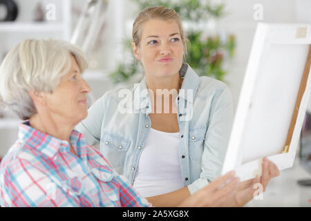 Senior donna guarda al photo frame con la figlia Foto Stock