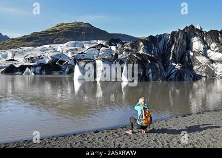 Escursionista prende le immagini del ghiacciaio Solheimajokull, Solheimajokull, lingua del ghiacciaio di Myrdalsjokull compresi ceneri vulcaniche, vicino anello stradale Foto Stock