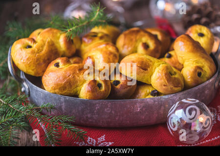 Un vassoio di pane appena sfornato in casa svedese zafferano tradizionali ciambelle, noto anche come lussekatter lussebullar o. Il giallo panini hanno uvetta e sono shap Foto Stock