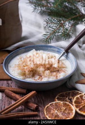 Tradizionale budino di riso noto anche come tomtegröt o risgrynsgröt svedese. Il budino di riso è in ceramica blu ciotola su una tavola di legno, con gingerbre Foto Stock