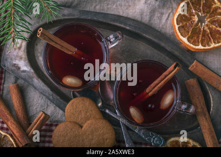 Vin brulé con bastoncini di cannella, visto da sopra. I bicchieri sono su un vecchio vassoio metallico circondato da a forma di cuore svedese tradizionale gingerbread cook Foto Stock