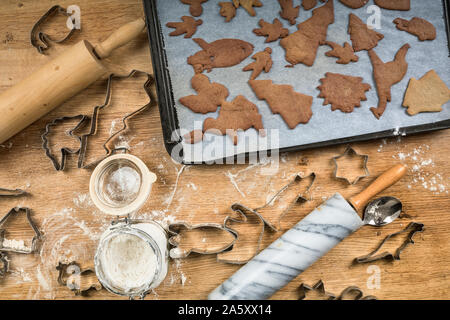 Gingerbread vassoio da forno su una tavola di legno, con biscotti e frese da taglio in varie forme come un riccio, Angelo, lumaca, mucca, rucola, dinosauro. C ar Foto Stock