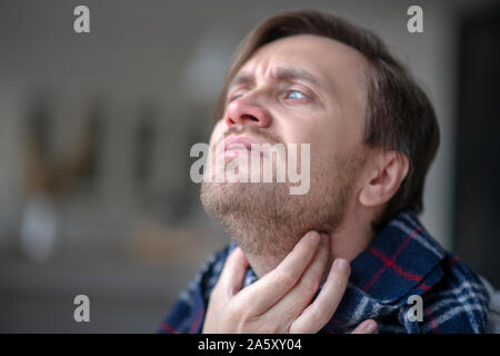 Blue-eyed man aventi terribile dolore al collo Foto Stock