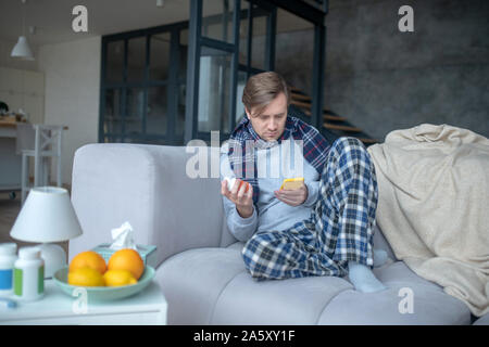 L'uomo prendendo il suo smartphone durante texting medico online Foto Stock