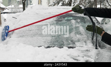La rimozione di neve dalla finestra anteriore della vettura con una scopa. Foto Stock