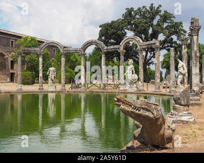 Colonne in rovina, sculture in marmo e coccodrillo sul lato curvo di canal-piscina Canopo. Parco architettonico, Villa Adriana, creato dell imperatore Adriano Foto Stock