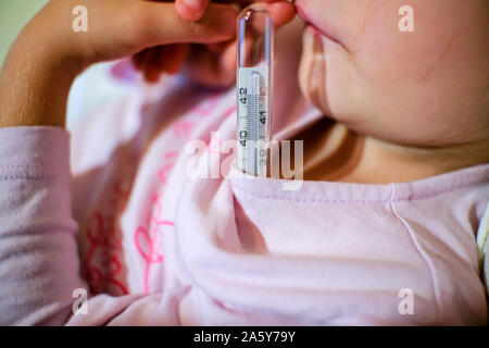 Misurare la febbre la temperatura con un termometro a un bambino piccolo che ragazza, la cura della salute Foto Stock