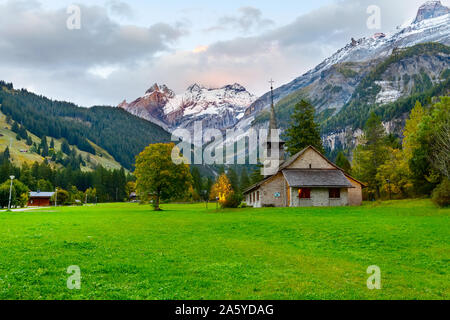 Panorama al tramonto di Kandersteg vecchia chiesa, Canton Berna, Svizzera, Europa, alberi d'autunno e al tramonto il panorama delle montagne Foto Stock