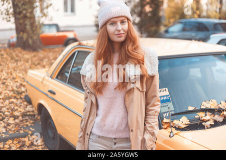 Elegantemente vestito redhead donna autista con auto retrò in autunno. Foto Stock