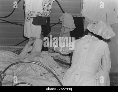 Il Tulare County, California. Farm Security Administration (FSA) camp per flussi migratori di lavoratori agricoli a Farmersville. L'infermiera di prodotti agricoli e la salute dei lavoratori Associazione Medica assiste malati donna migrante in attesa medico da Dorothea Lange 1895-1965, datata 19380101 Foto Stock