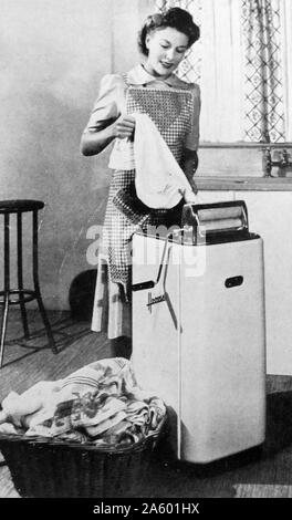 Un abbigliamento parnall ritorsa che acqua drenata dai vestiti bagnati, British 1950. Foto Stock