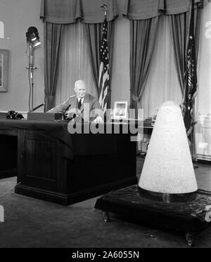 Presidente Dwight Eisenhower dando un discorso televisivo nella Casa Bianca circa la scienza e la sicurezza nazionale. Nel discorso egli spiega come il missile sperimentale che era stato nello spazio e indietro (a forma di cono di un oggetto verso destra). 1957 Foto Stock