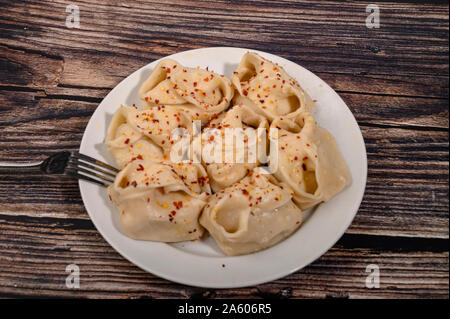 Bollito di manti con la carne su un piatto con spezie su di un tavolo di legno Foto Stock