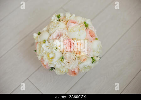 Bouquet nozze giacente sul tappeto grigio durante la preparazione prima della celebrazione. Vista laterale del decoro rose,le peonie fiori e foglie bouquet. Foto Stock