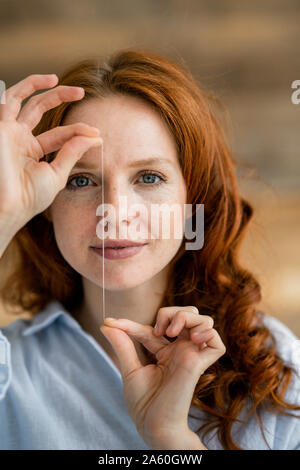 Ritratto di donna redheaded thread di trattenimento del filo interdentale Foto Stock