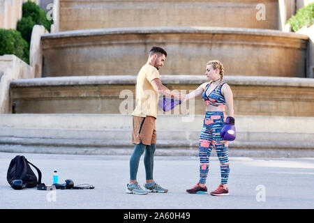 Fitness coach praticando la boxe con classe giovane donna all'aperto nella città di mettere sul guanto di boxe Foto Stock