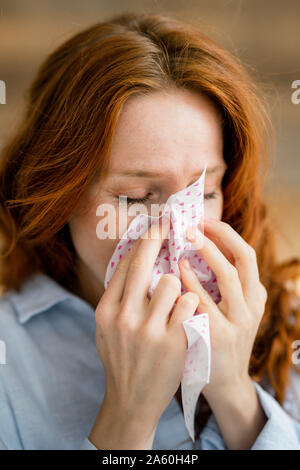 Redheaded donna soffia il naso Foto Stock