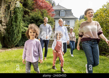 Felice famiglia estesa a camminare nel giardino della loro casa Foto Stock