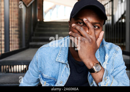 Ritratto di uomo che ricopre la faccia con la mano Foto Stock