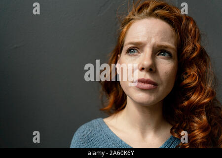 Ritratto di pensieroso redheaded donna contro uno sfondo grigio Foto Stock