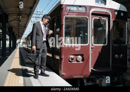 Giovane imprenditore su una piattaforma del treno controllando il tempo Foto Stock