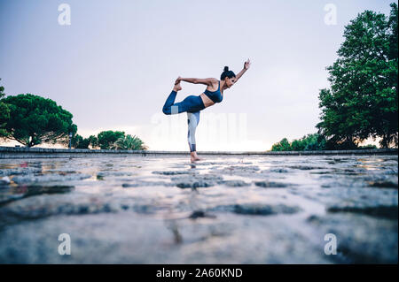 Donna pratica lo yoga sotto la pioggia, posizione ballerino Foto Stock