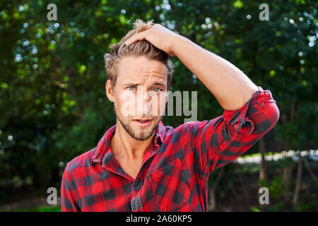 Ritratto di giovane uomo che indossa camicia a scacchi all'aperto Foto Stock