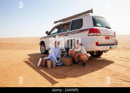 Tourist avente una pausa caffè con il suo driver locale nel deserto Wahiba Sands, Oman Foto Stock