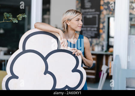 La donna in piedi di fronte a lei coffee shop, tenendo icecream segno Foto Stock