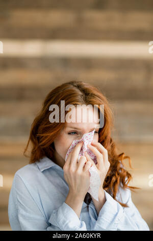 Redheaded donna soffia il naso Foto Stock