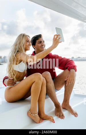 Coppia giovane godendo una giornata estiva su una barca a vela Foto Stock