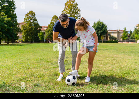 Padre e figlia a giocare a calcio su un prato Foto Stock