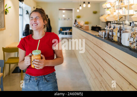 Felice giovane donna con un smoothie in un cafe Foto Stock