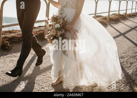 Close-up della sposa e lo sposo a piedi sul sentiero del litorale Foto Stock