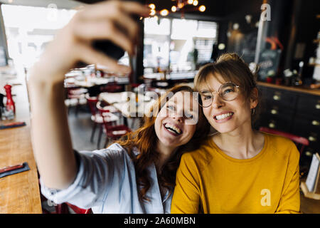 Due happy amici di sesso femminile prendendo un selfie in un ristorante Foto Stock