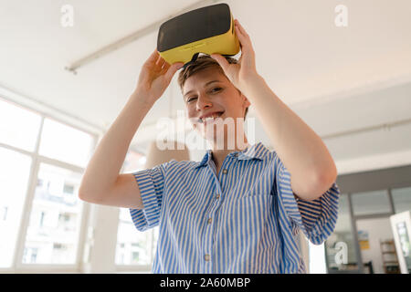 Ritratto di sorridere imprenditrice con occhiali VR in office Foto Stock