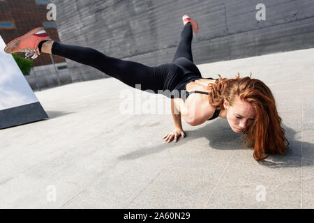 Sporty giovane donna facendo acrobazie all'aperto Foto Stock