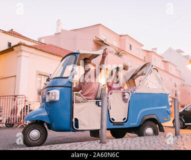 Un Tuk Tuk driver fornendo il tour della città per un turista, Lisbona, Portogallo Foto Stock