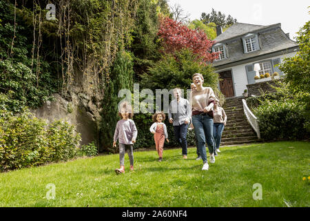 Felice famiglia estesa a camminare nel giardino della loro casa Foto Stock