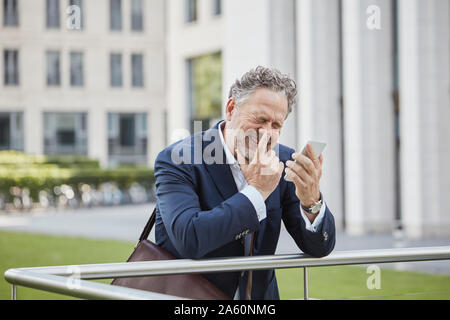 Happy businessman maturo con lo smartphone in città Foto Stock