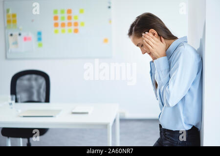 Giovane imprenditrice che soffrono di mal di testa in ufficio Foto Stock